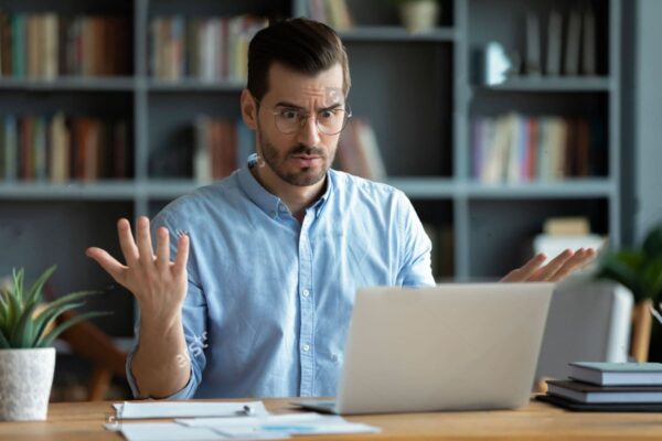 stock photo unhappy young caucasian male worker in glasses look at laptop screen shocked by gadget breakdown or cc